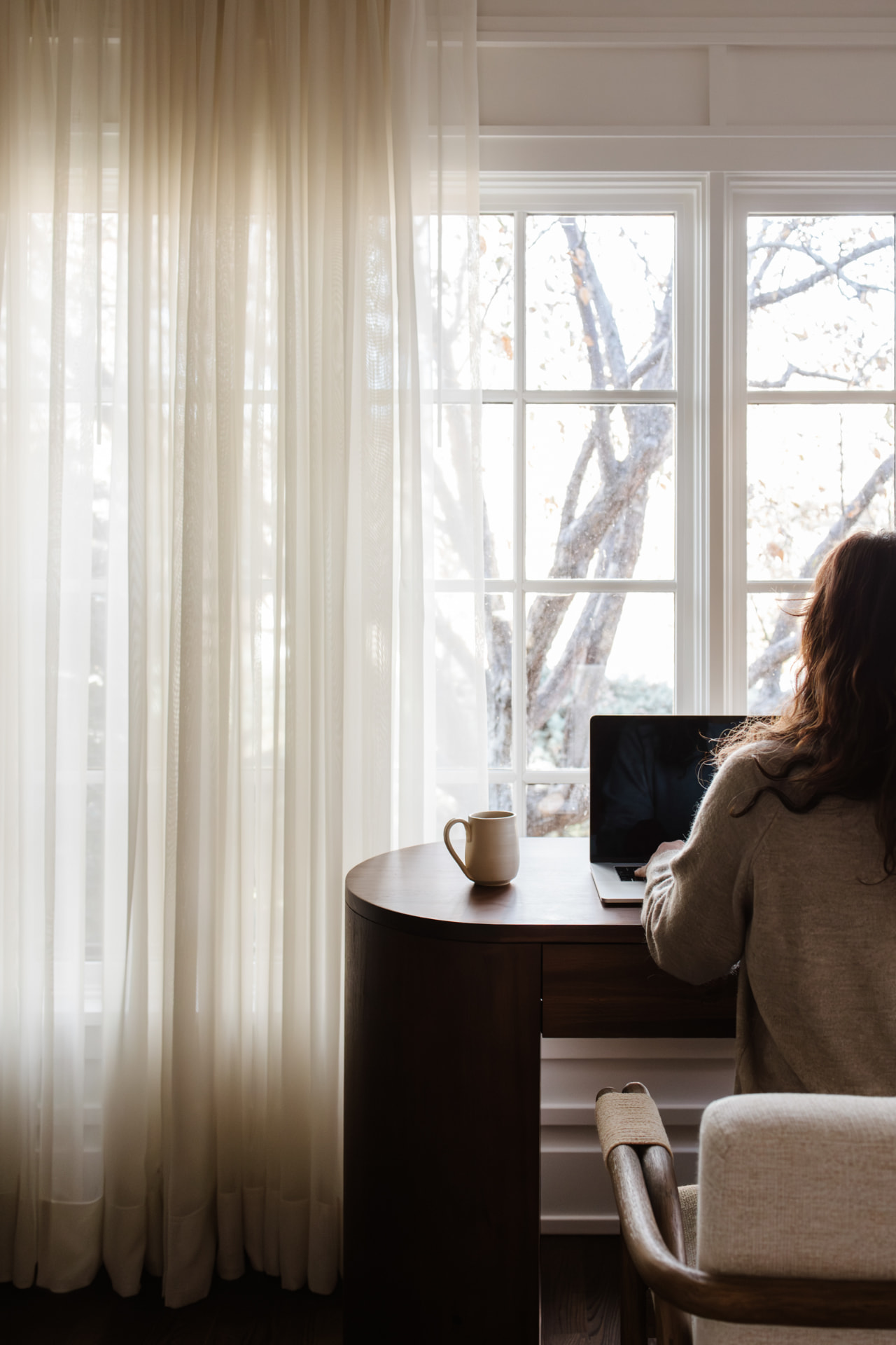 A person working at a desk beside a bright window.
