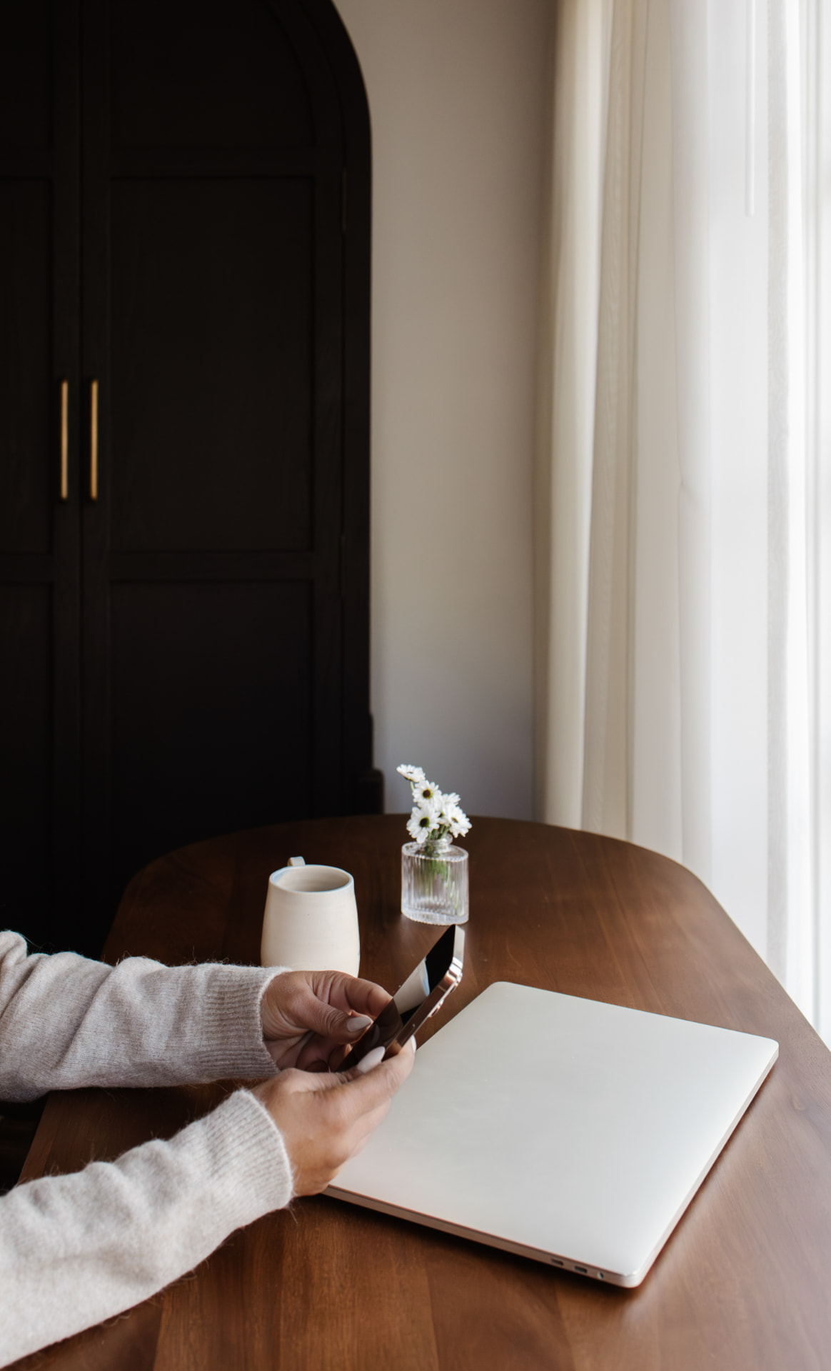 A phone, notebook, and laptop on a busy work desk.