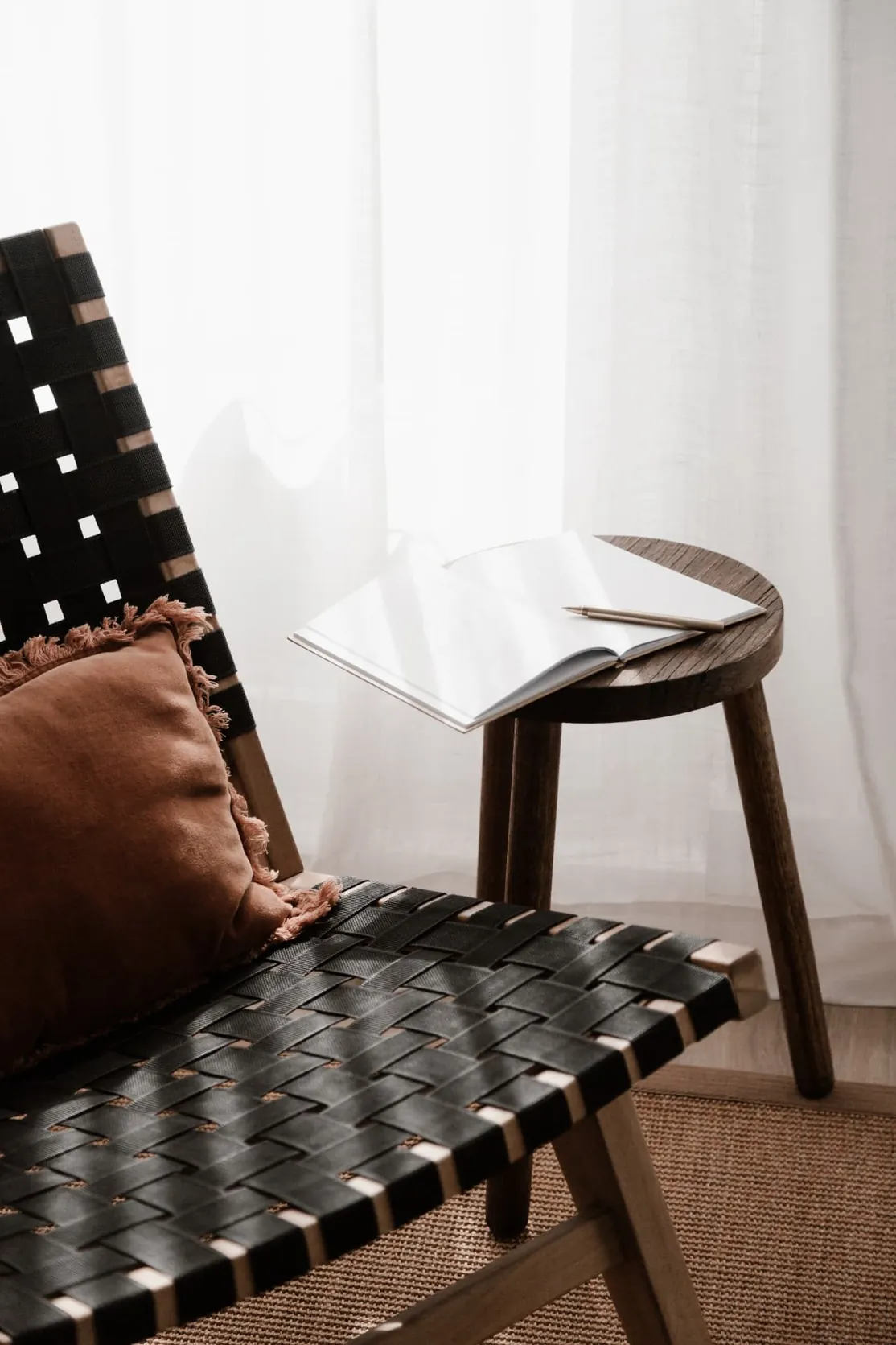 A chair beside a small table with an open notebook and pen.