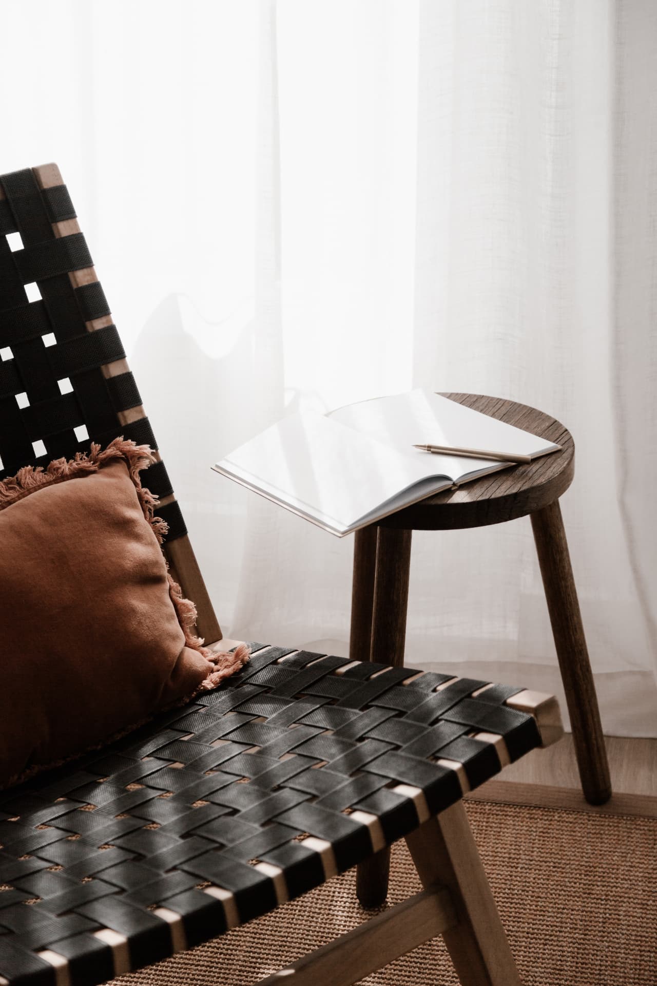 A chair beside a small table with an open notebook and pen.