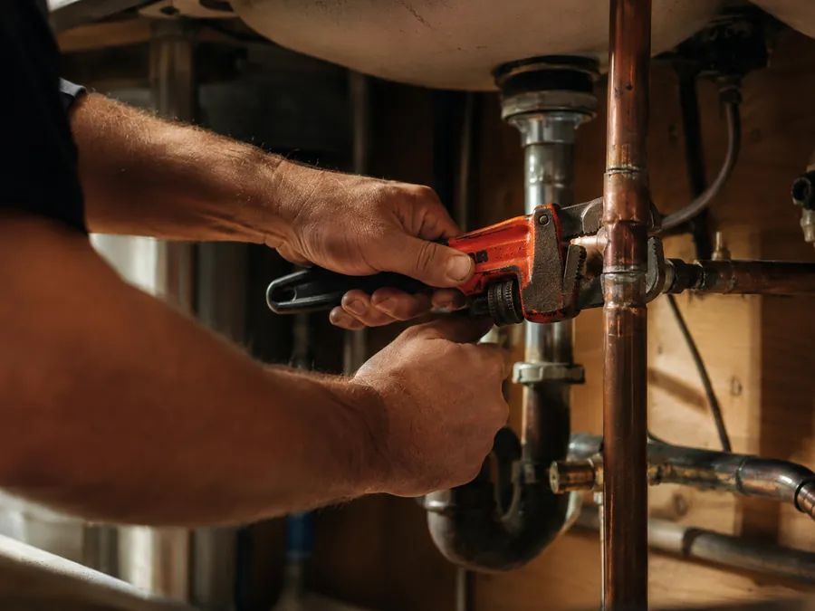A plumber tightening a copper pipe